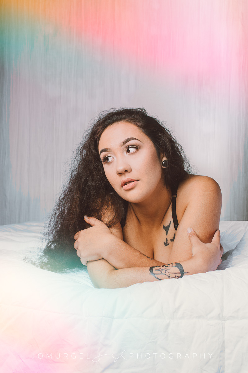 woman, shrouded by curtain, in black bra looking at camera