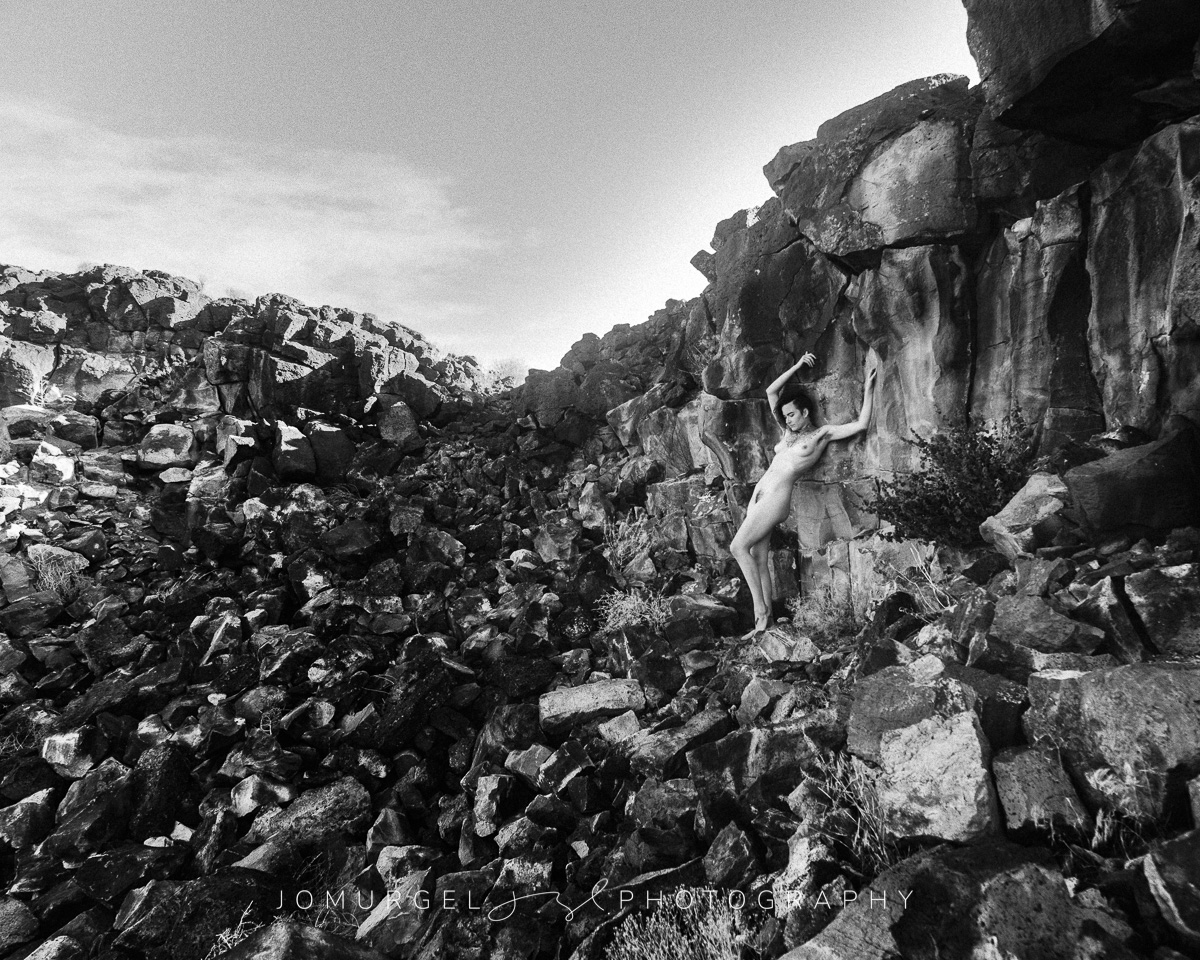 nude woman posed on rocks in black and white